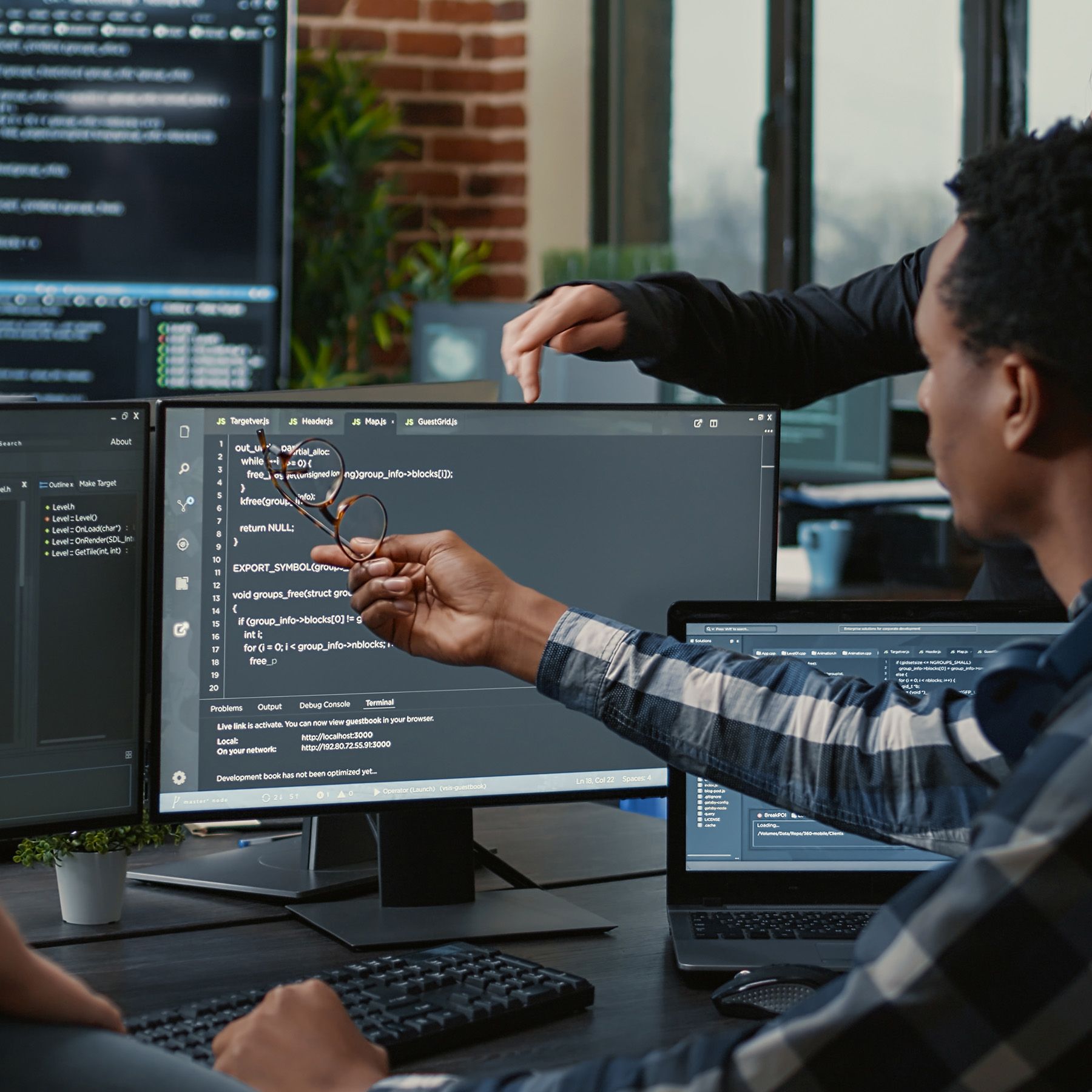 Two developers reviewing code together at a desk of monitors